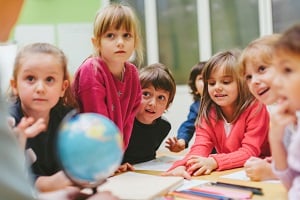 Young children gathered around a table in class